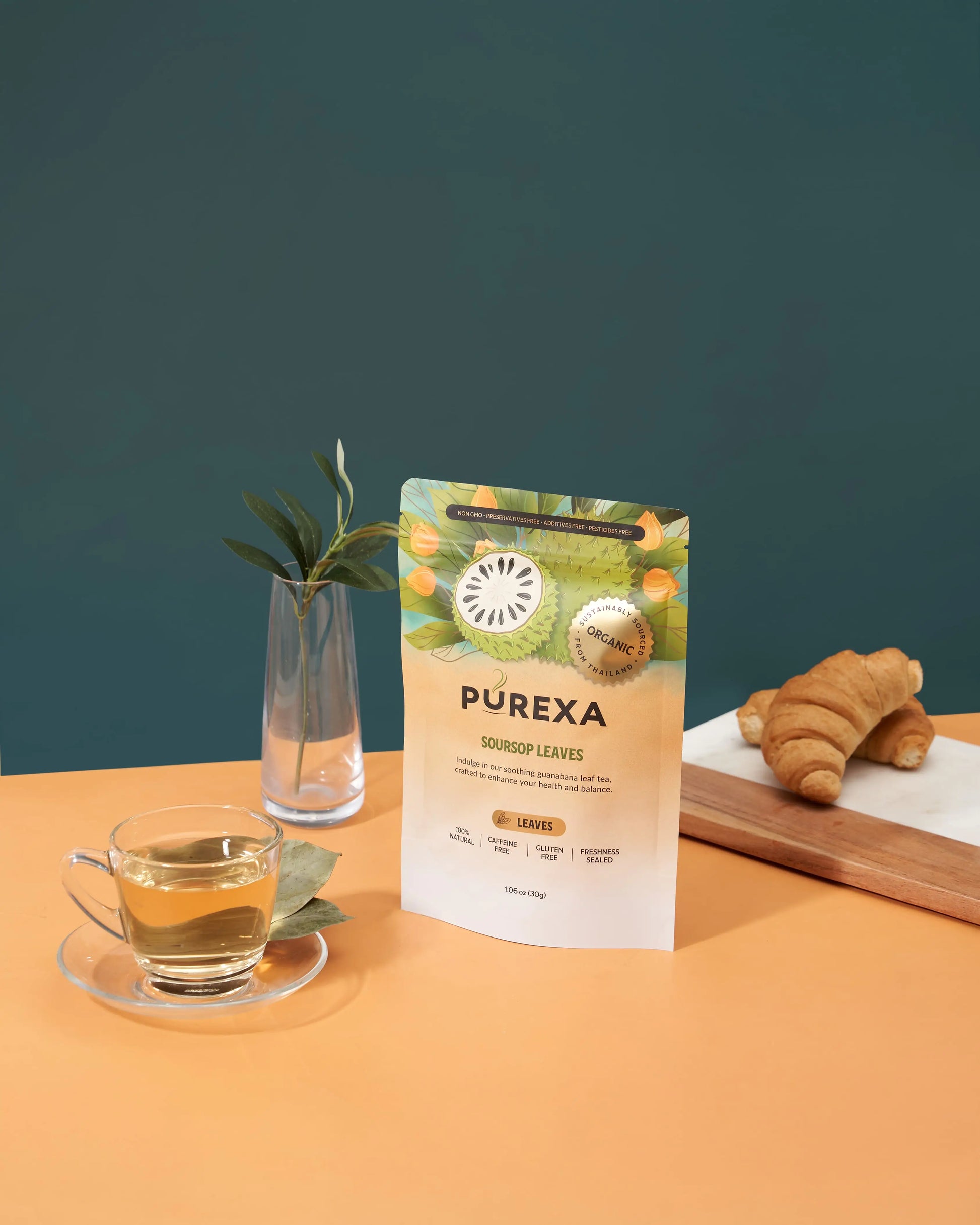 PUREXA soursop whole leaves pouch with a cup of tea, dried leaves, vase, and croissants