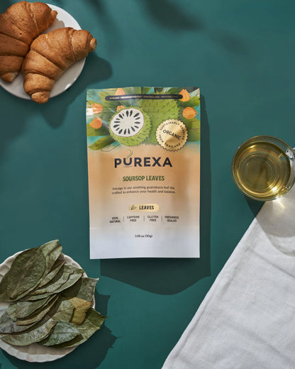 Overhead view of PUREXA soursop leaves pouch with dried leaves, brewed tea, and croissants